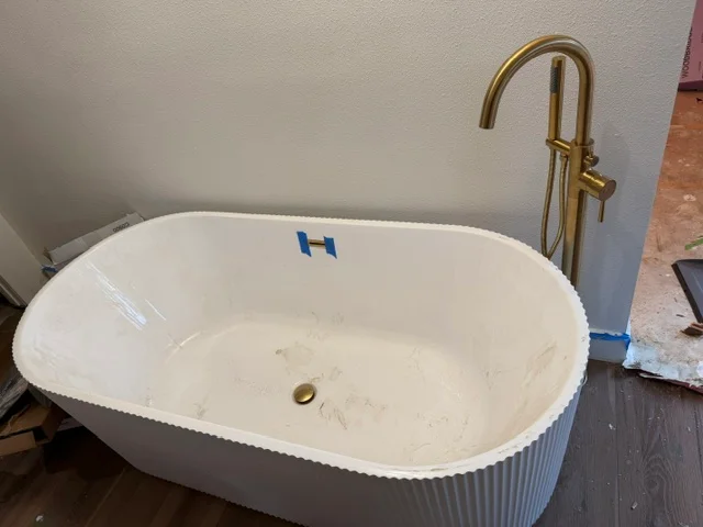 White freestanding soaking tub with brass faucet during installation
