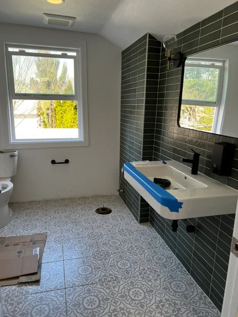 Modern bathroom with black tile shower, patterned concrete floor, and floating vanity