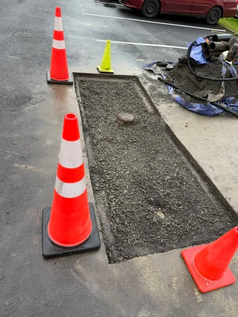 Sewer line excavation showing trench with new pipe installation and safety cones