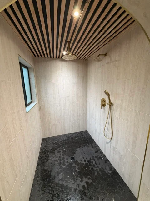 Modern bathroom shower with wood-look tile walls, concrete floor, and black slatted ceiling