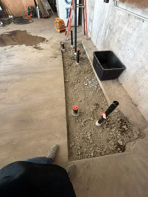 Underground drainage trench with gravel base and PVC pipe installation along foundation